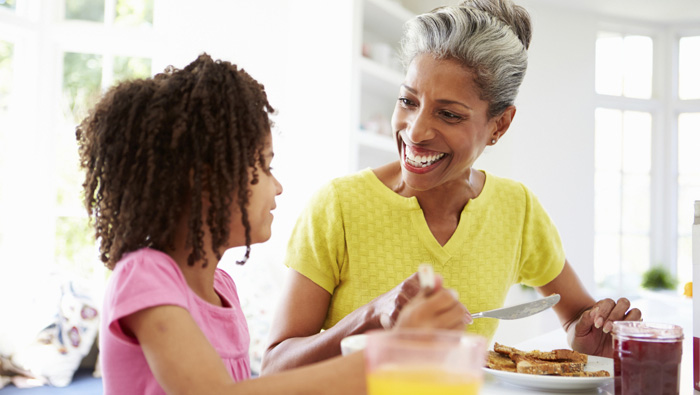 grandmother and granddaughter eating breakfast at the kitchen table