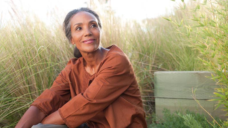 Serene mature woman sitting in a sunny field