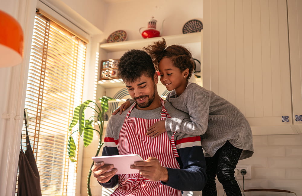 daughter helping father with recipe on tablet