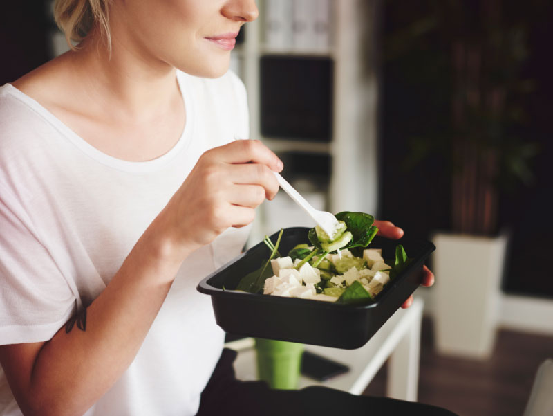 Woman eating salad at the office. 