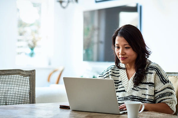 Woman working from home on a laptop at her kitchen table.