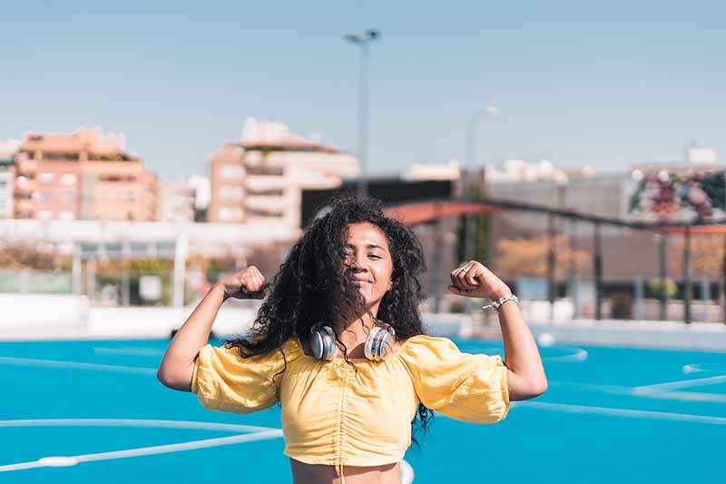 Young  African American girl smiling in yellow T-shirt raising her arms