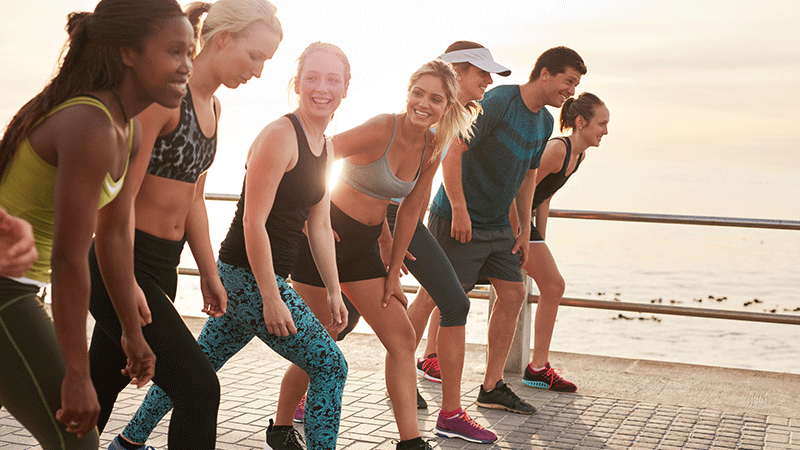 Group of people smiling on the beach preparing for a race