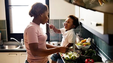 Child feeding mother in the kitchen Dietary Recommendations for Healthy Children
