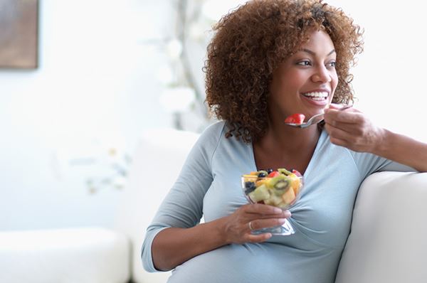 pregnant woman eating fruit on couch pregnant woman eating fruit on couch